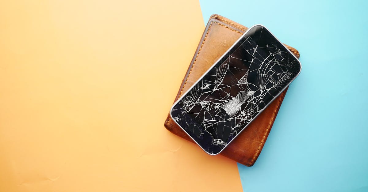 Close-up of a broken smartphone on a wallet, showcasing damaged screen.
