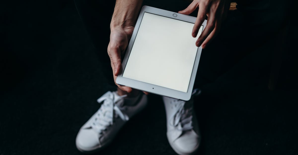 Close-up of hands holding a blank tablet screen with white sneakers. Ideal for tech themes.