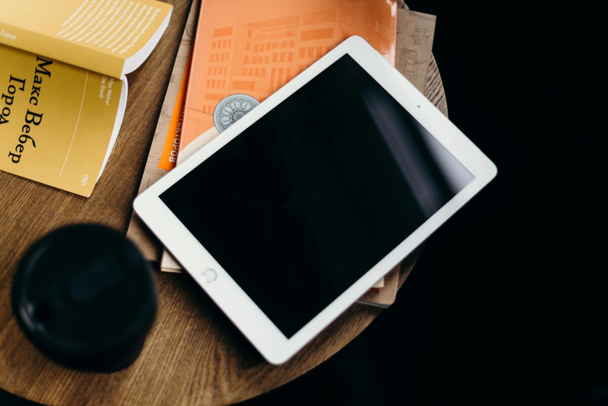 A cozy home setup featuring a tablet with blank screen on a table with books, creating a relaxed atmosphere.