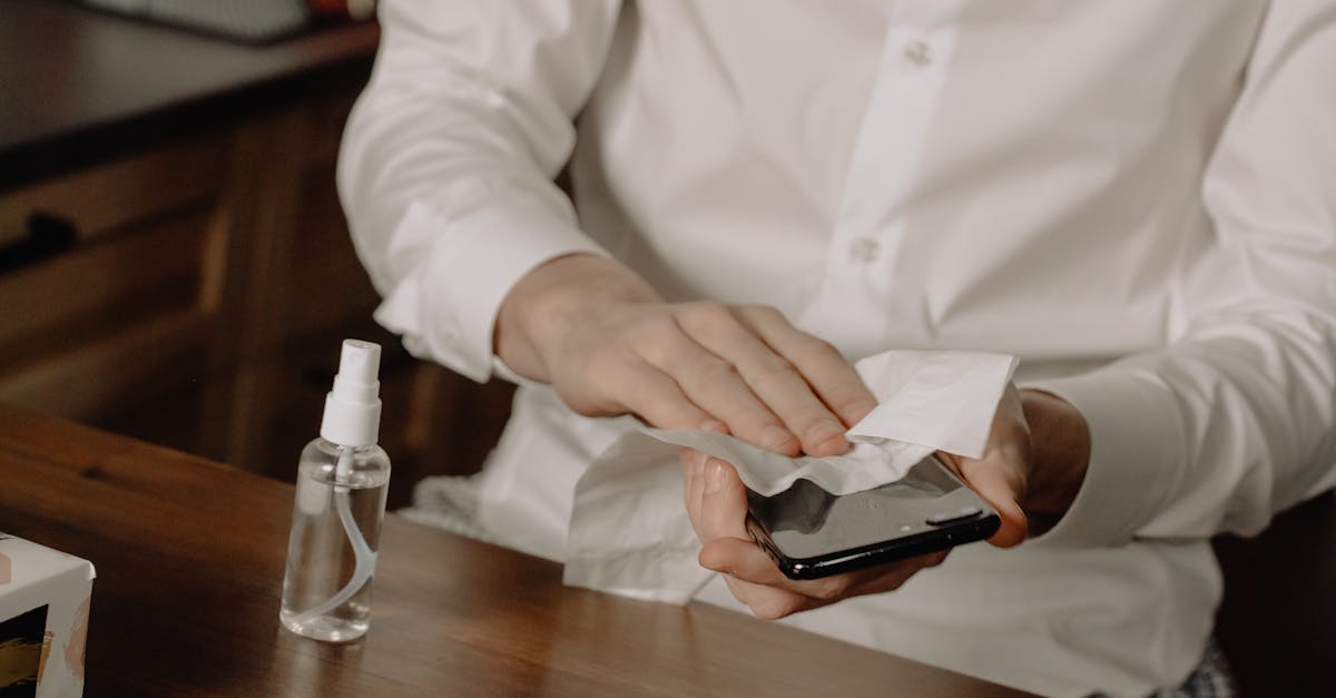 A person sanitizes their smartphone at a table, promoting healthy hygiene in home settings.