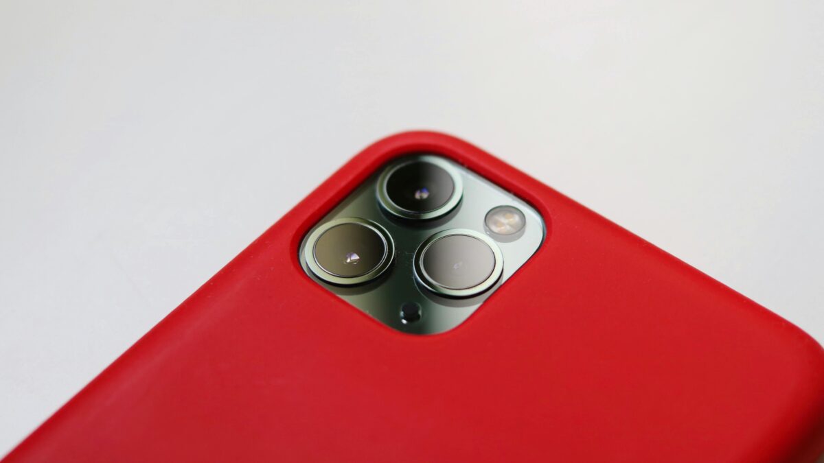 Macro shot of a smartphone camera with a red case, highlighting lens detail.