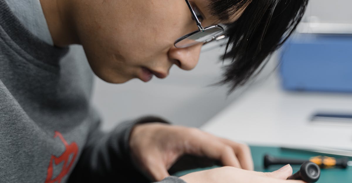 Young engineer examining electronic components at a workspace indoors.