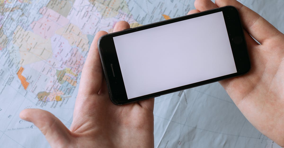 Hands holding a smartphone with blank screen above a world map, showcasing global travel planning concept.