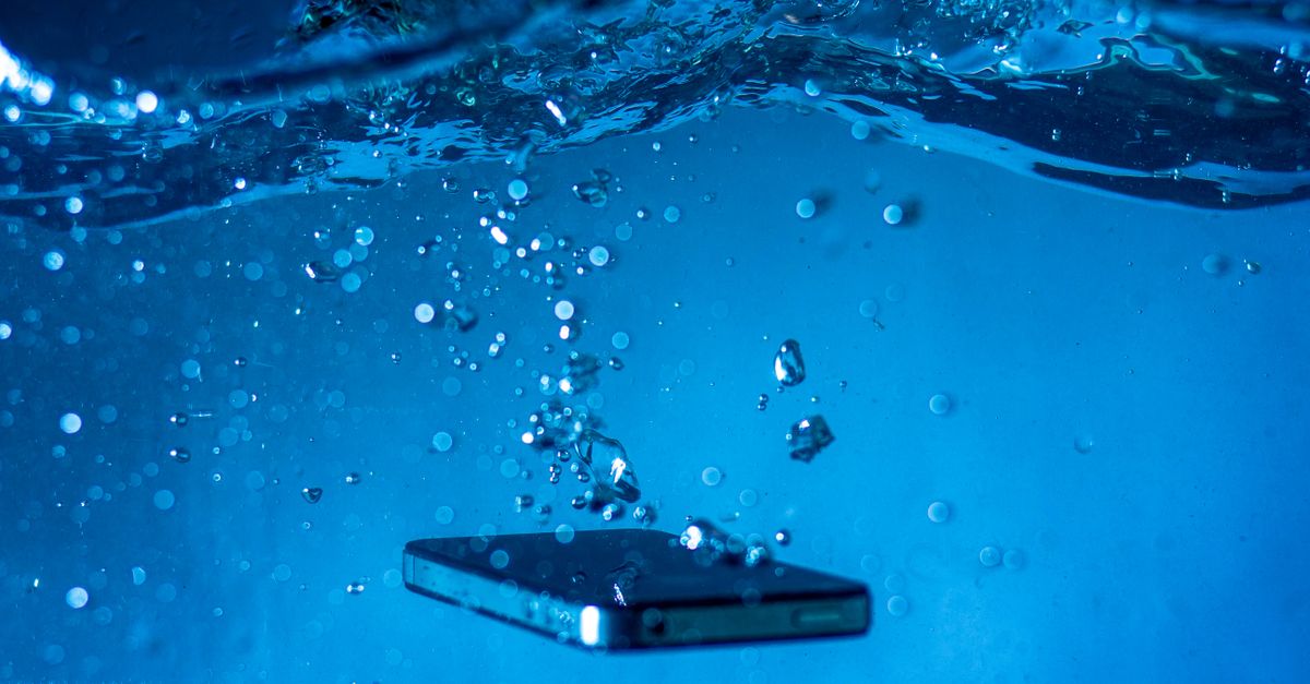 A smartphone submerged in water with bubbles rising around it, showcasing a dynamic underwater scene.