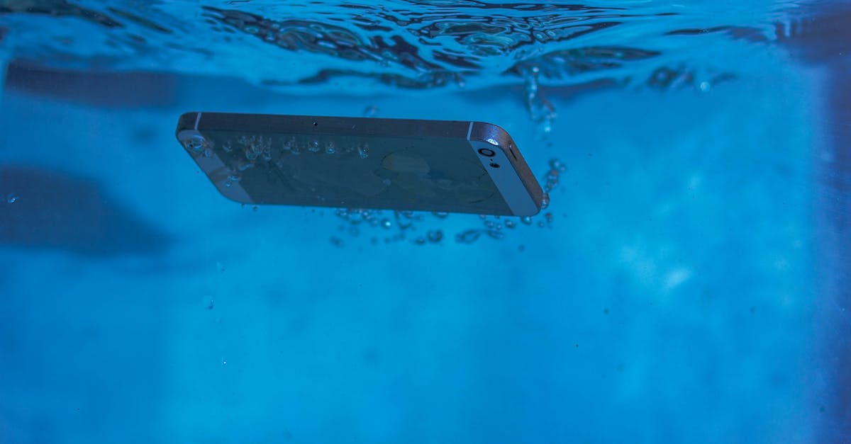 A smartphone underwater displaying air bubbles and motion in vivid blue water.